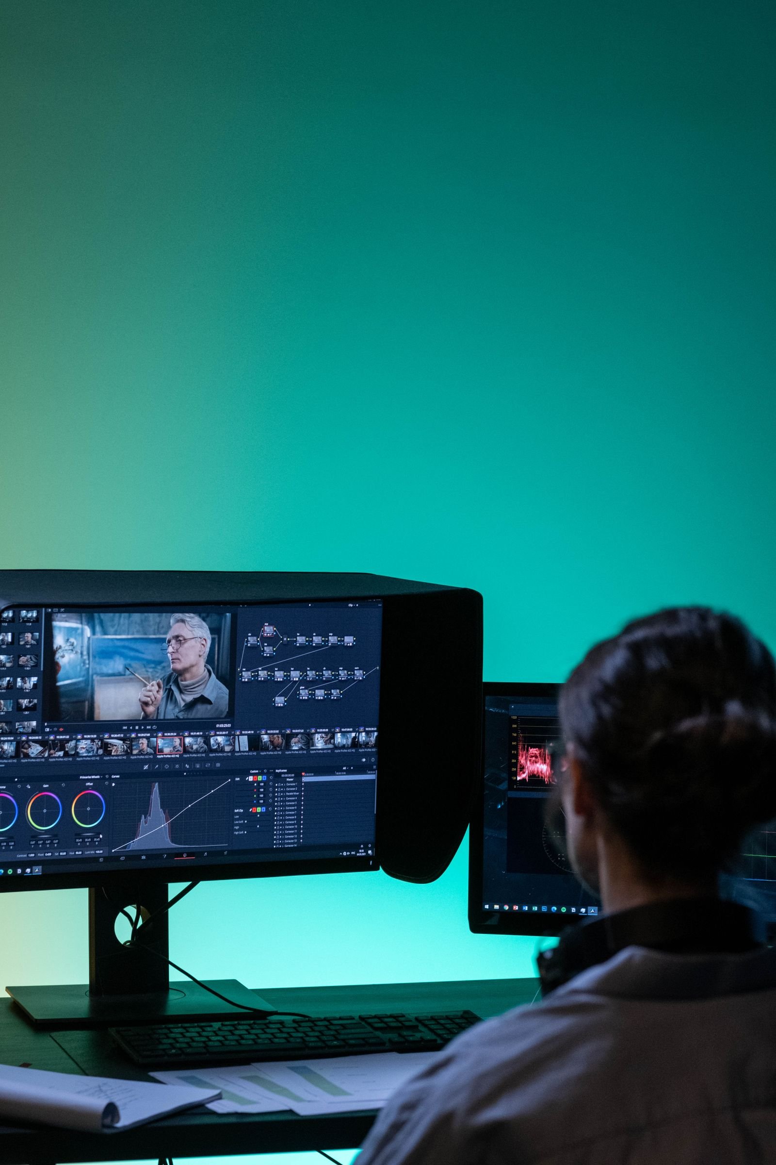 Editor working in DaVinci Resolve on dual monitors in a dark room