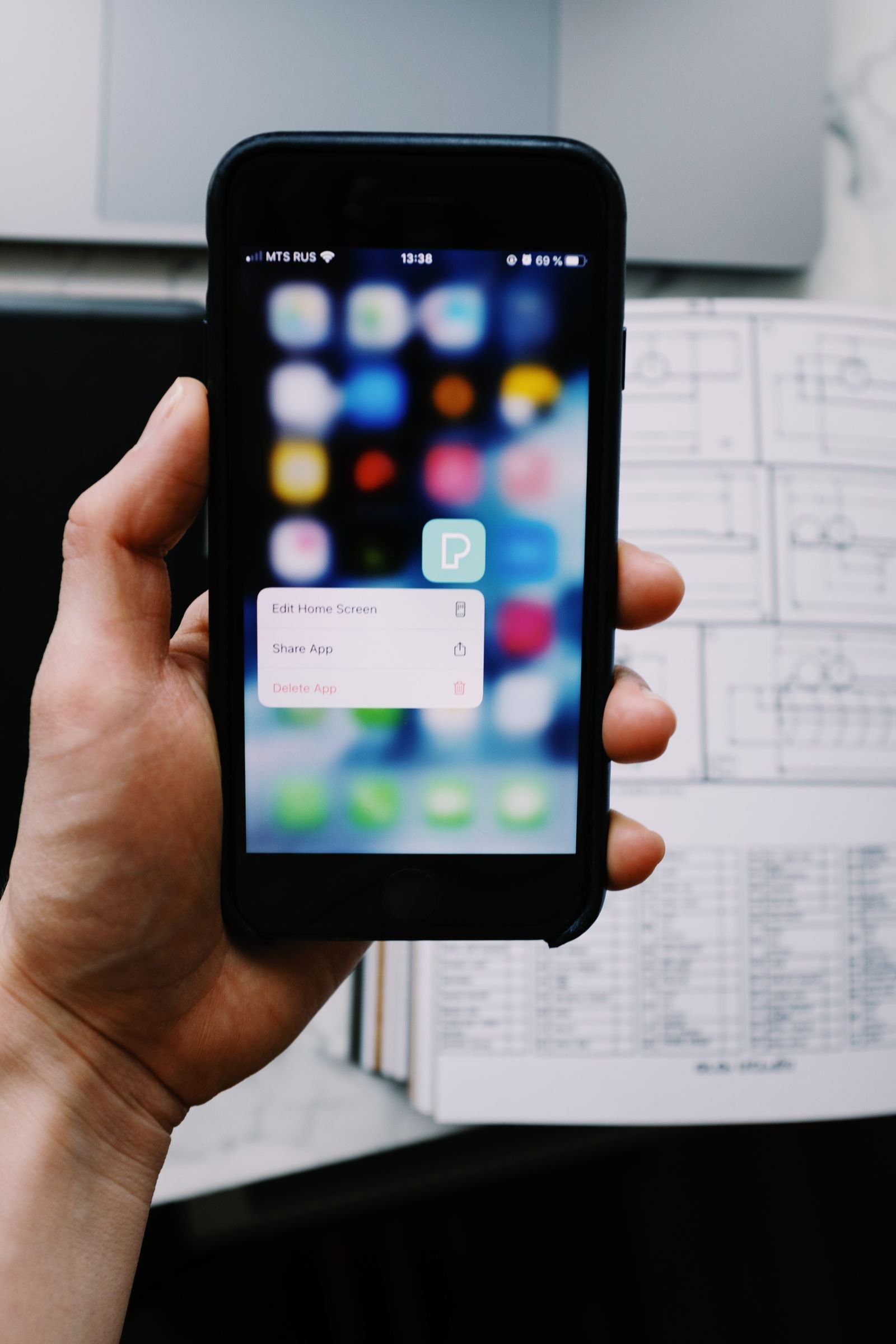 Hand holding an iPhone showing an app screen while clearing cache in iOS 26