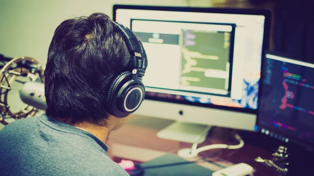iOS developer with headphones writing app code at a workstation