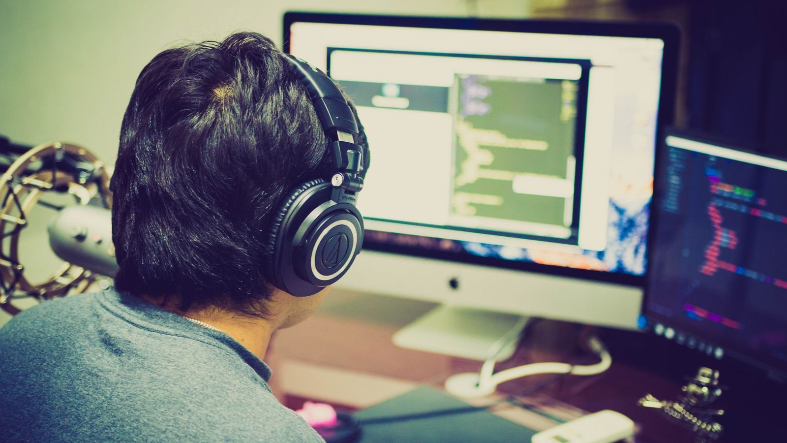 iOS developer with headphones writing app code at a workstation