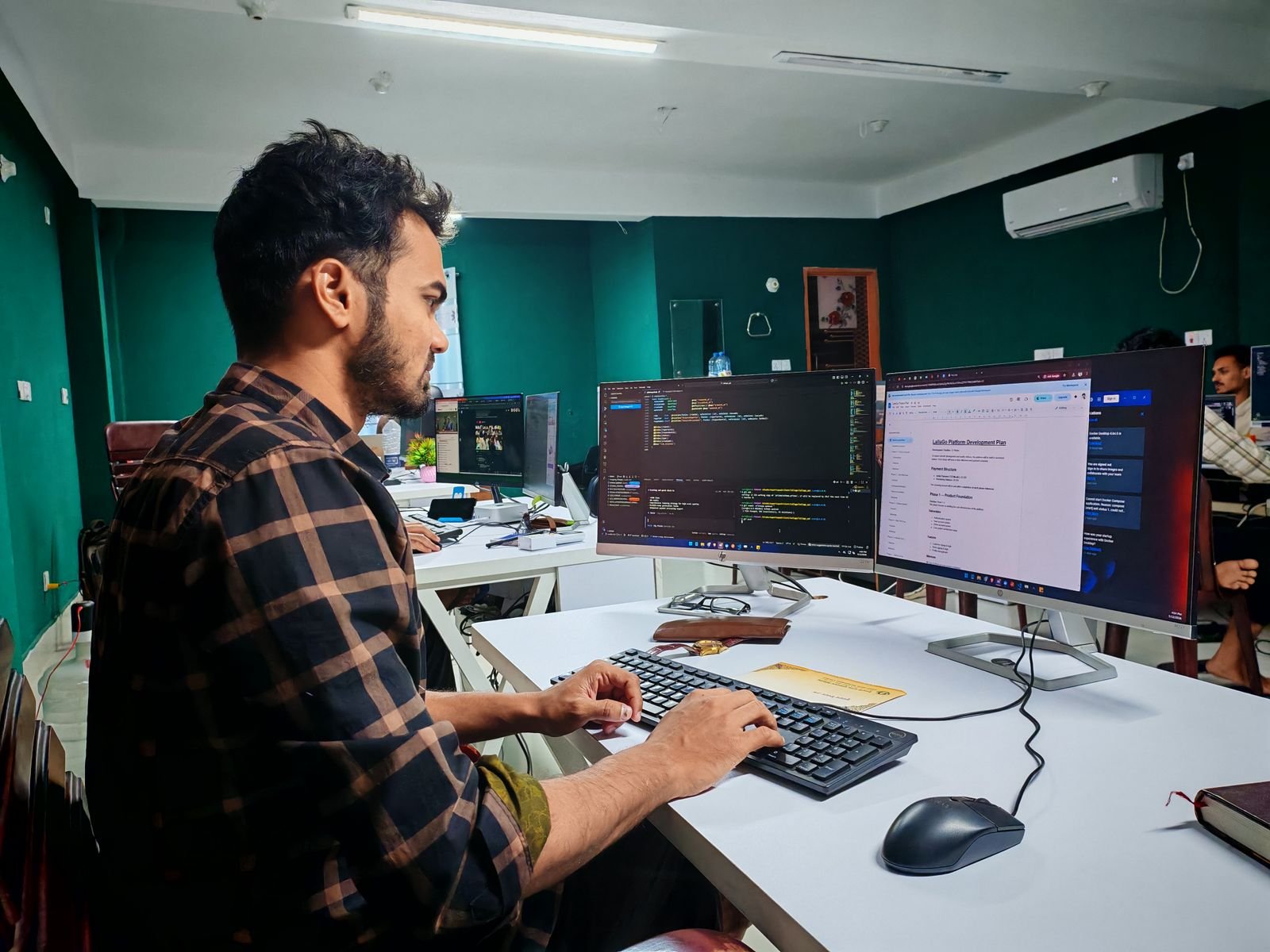 Developer working on a dual monitor Mac setup with Xcode open