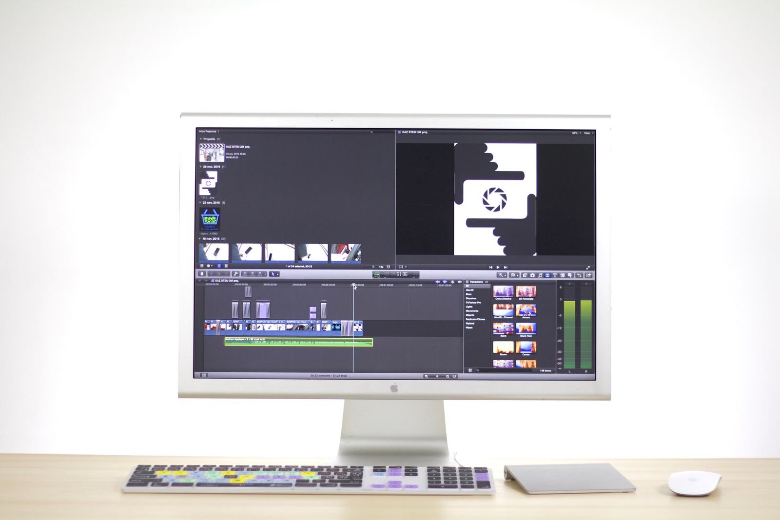 Large monitor showing a video editing timeline on a Mac setup