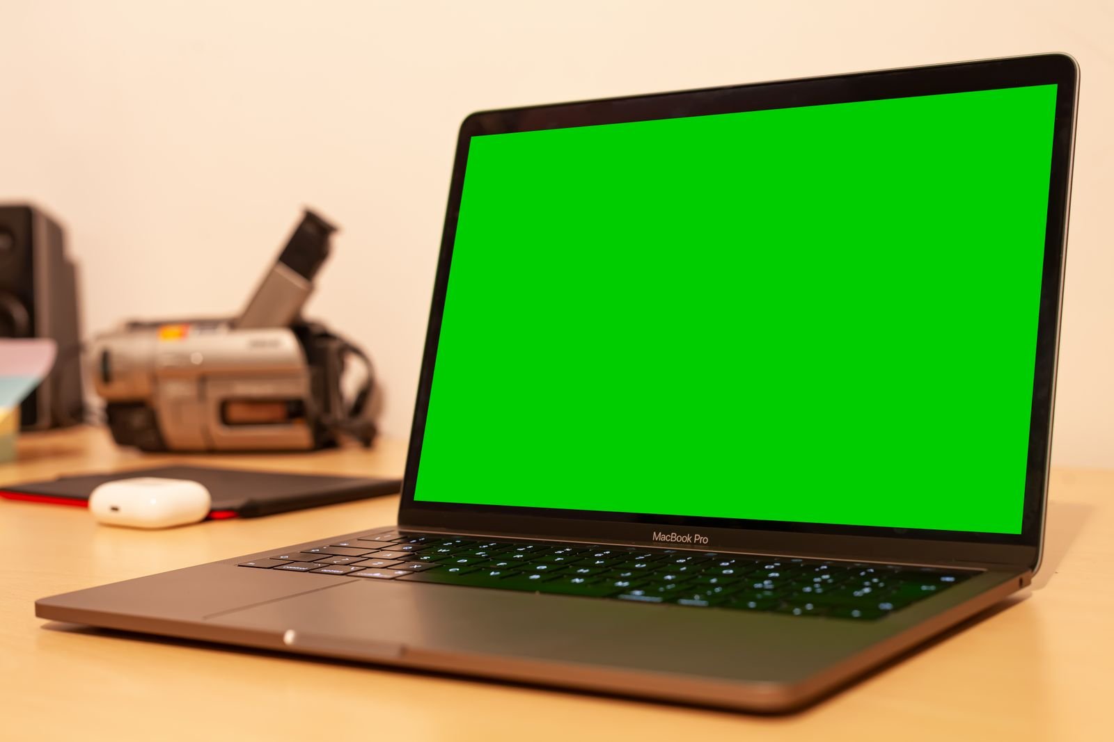 MacBook on a desk being used for video editing with green screen footage