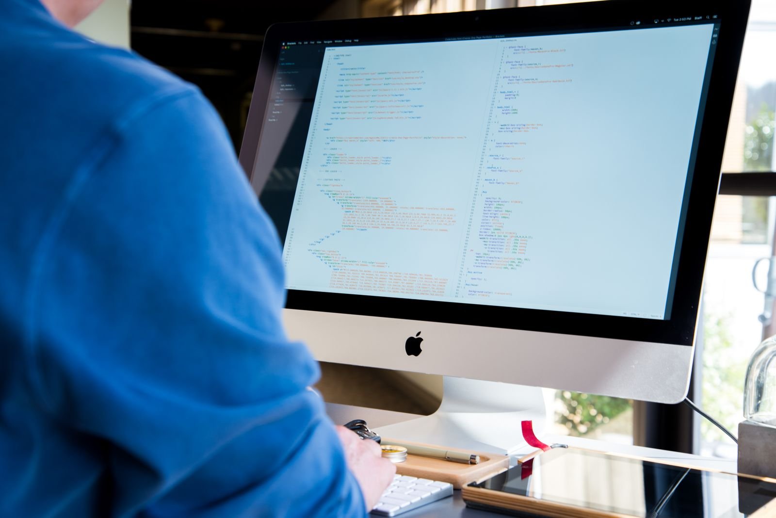 Programmer writing code on an iMac while building a macOS app