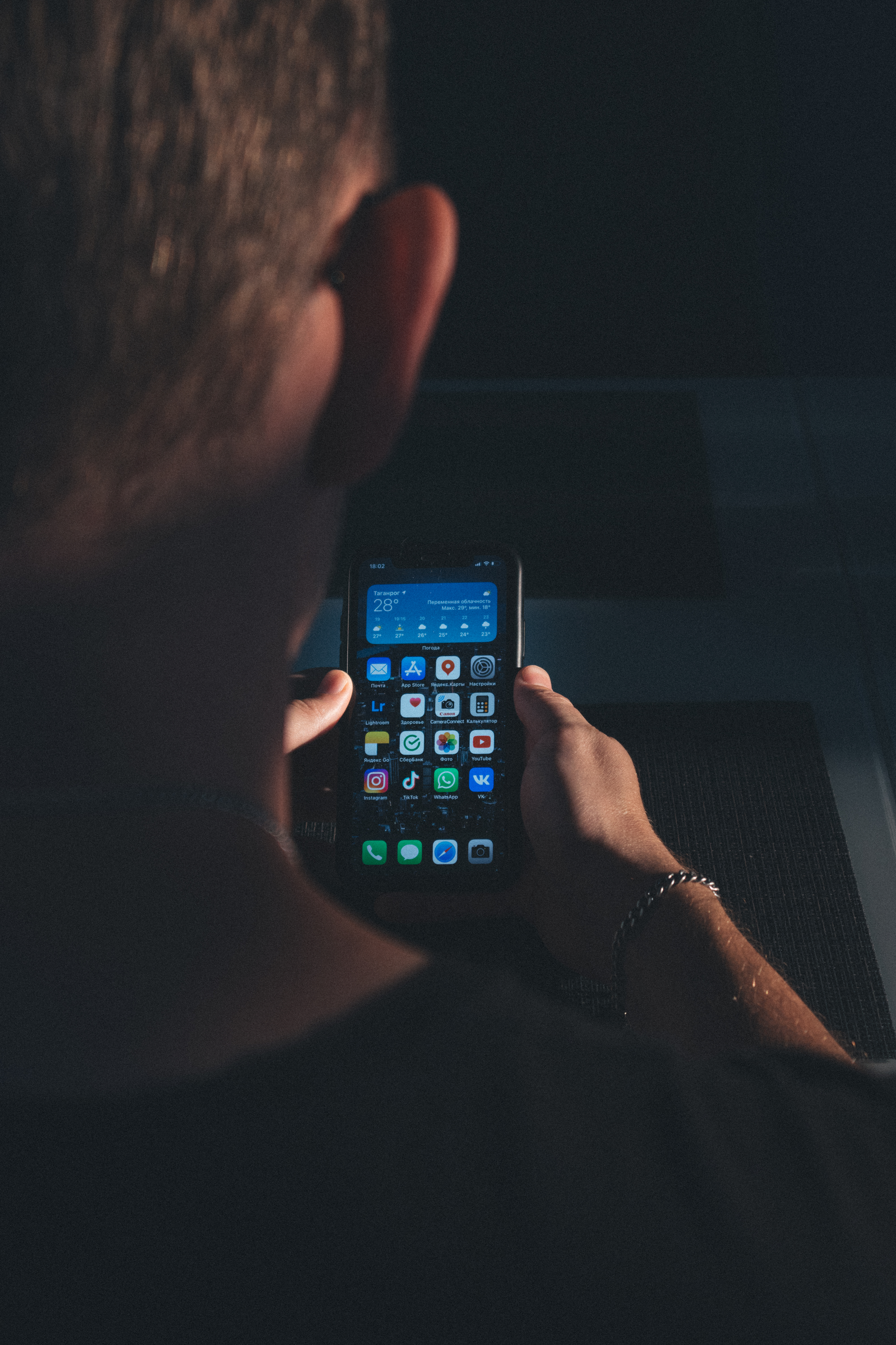 Person holding an iPhone while re-adding the screen recording control in iOS 26